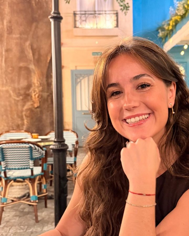 Cris sonriendo, con la barbilla apoyada en la mano, sentada en la terraza de un restaurante